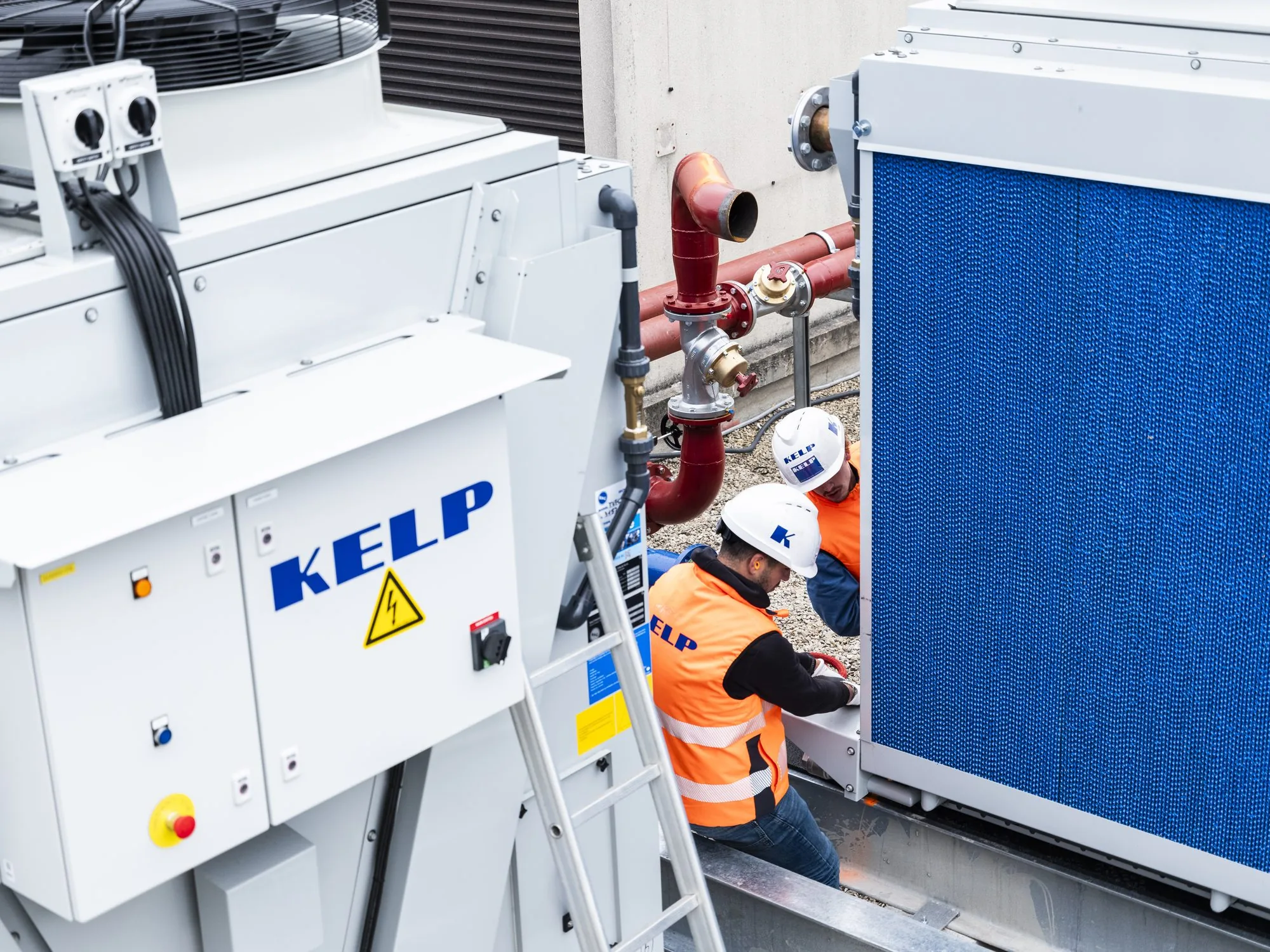 Two KELP technicians at the foot of an adiabatic dry cooler, on a roof